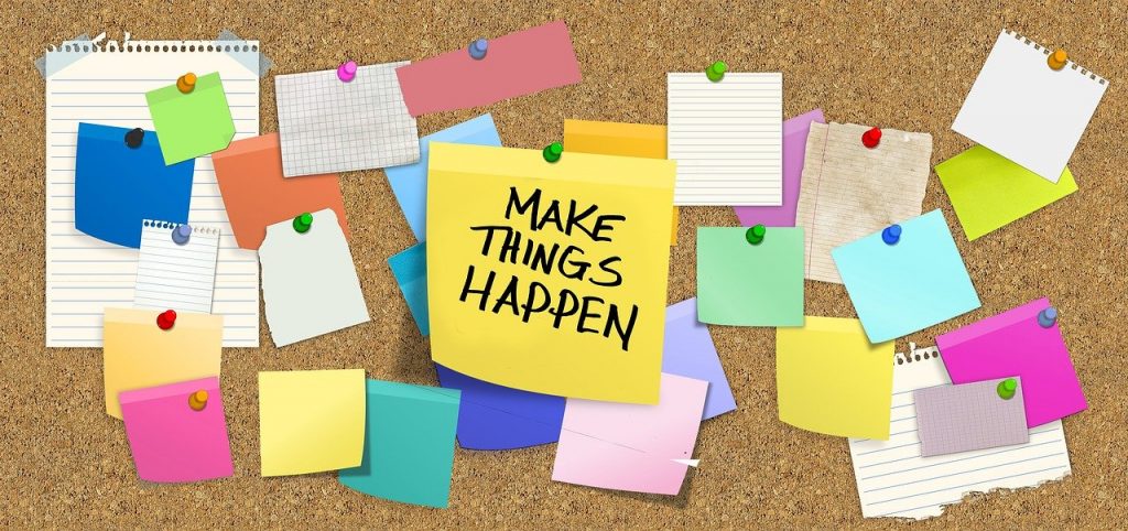 A brown board with Post-its and slogan - "Make things happen."